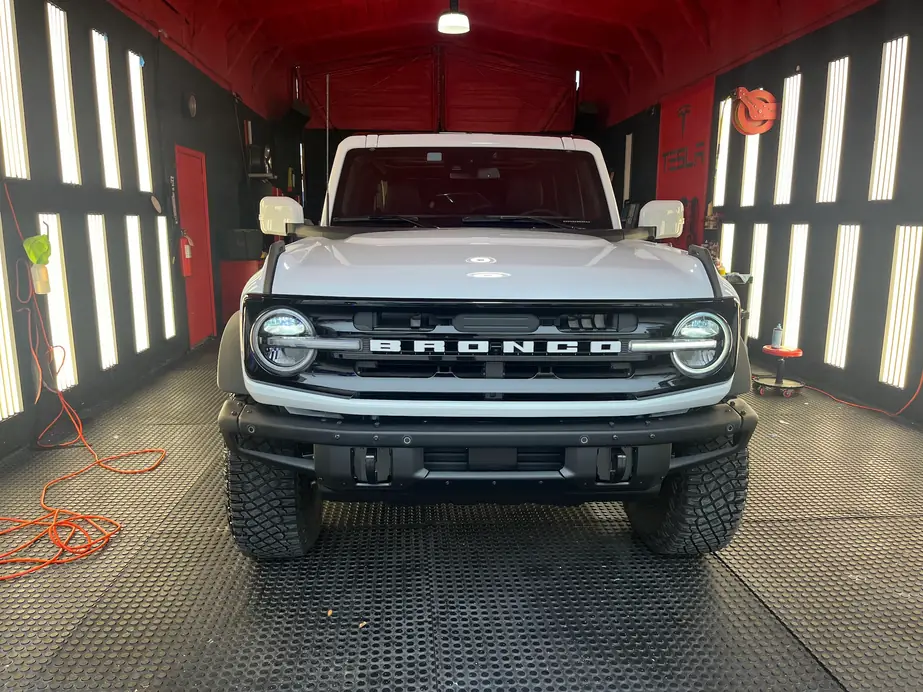 White Ford Bronco nose-in to the red Dr. Detail bay between two walls of vertical LED tubes
