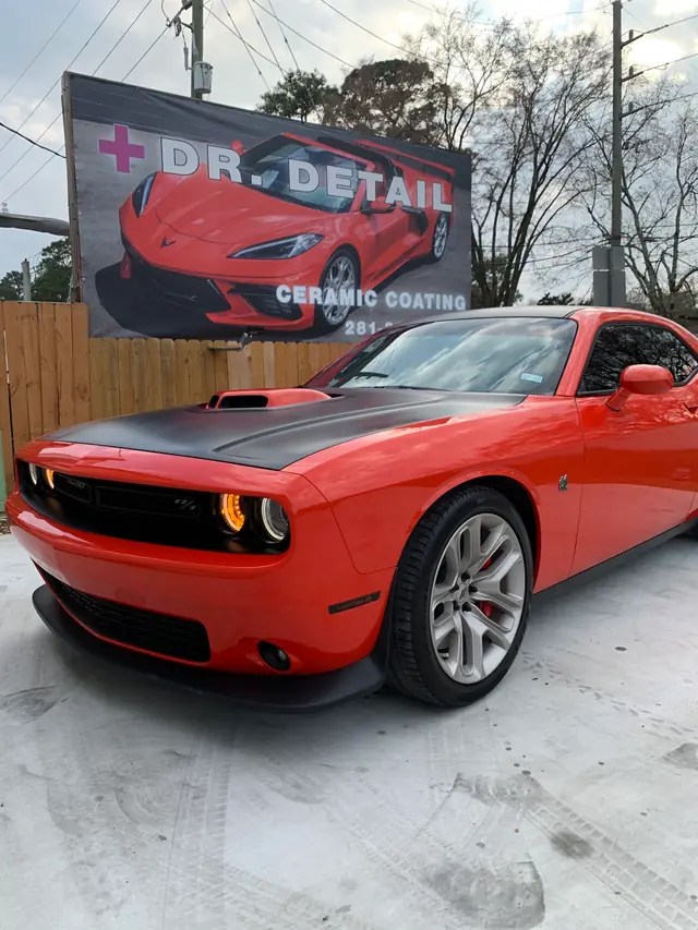 Orange Dodge Challenger parked in front of the red Dr. Detail Ceramic Coatings sign
