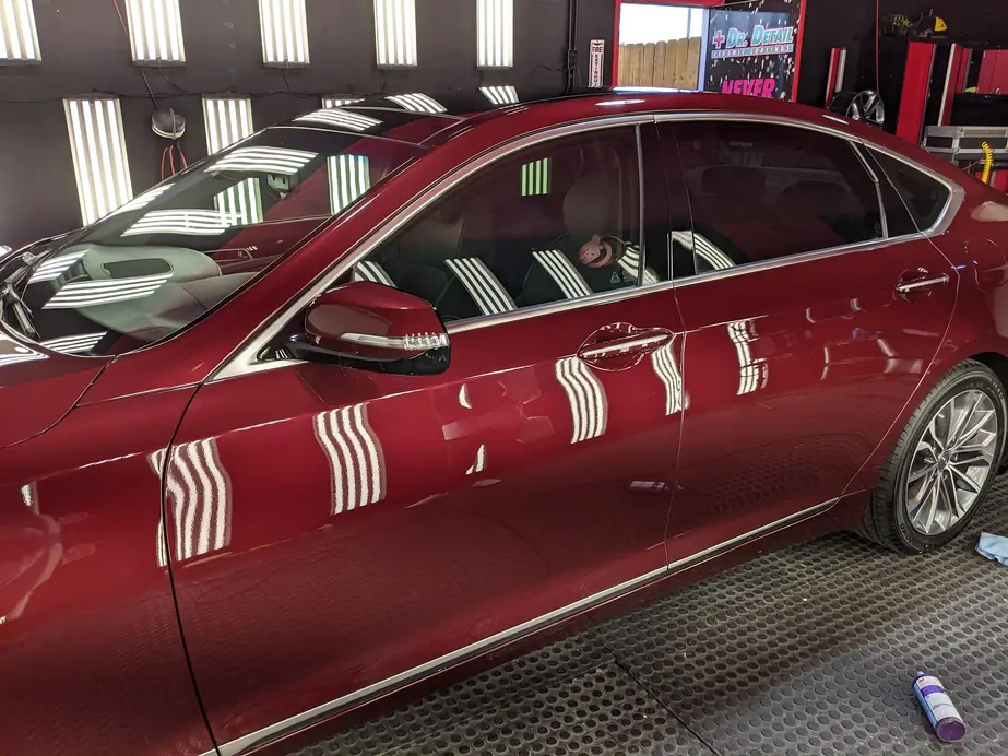 Deep red sedan in the Dr. Detail bay, light-wall stripes mirrored down the doors