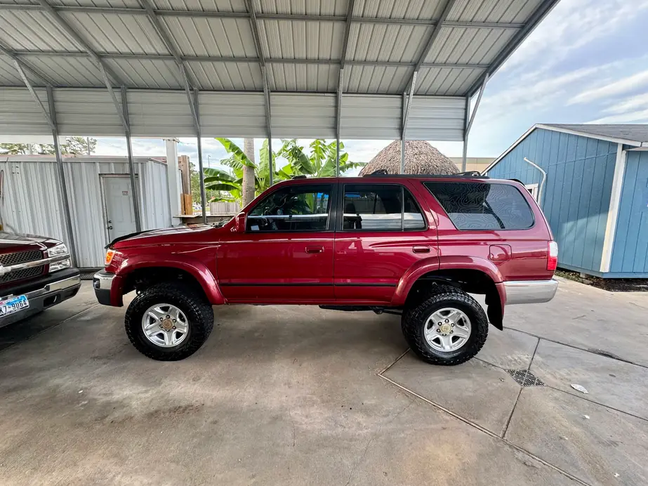 Maroon Toyota 4Runner finished and parked under the shop carport